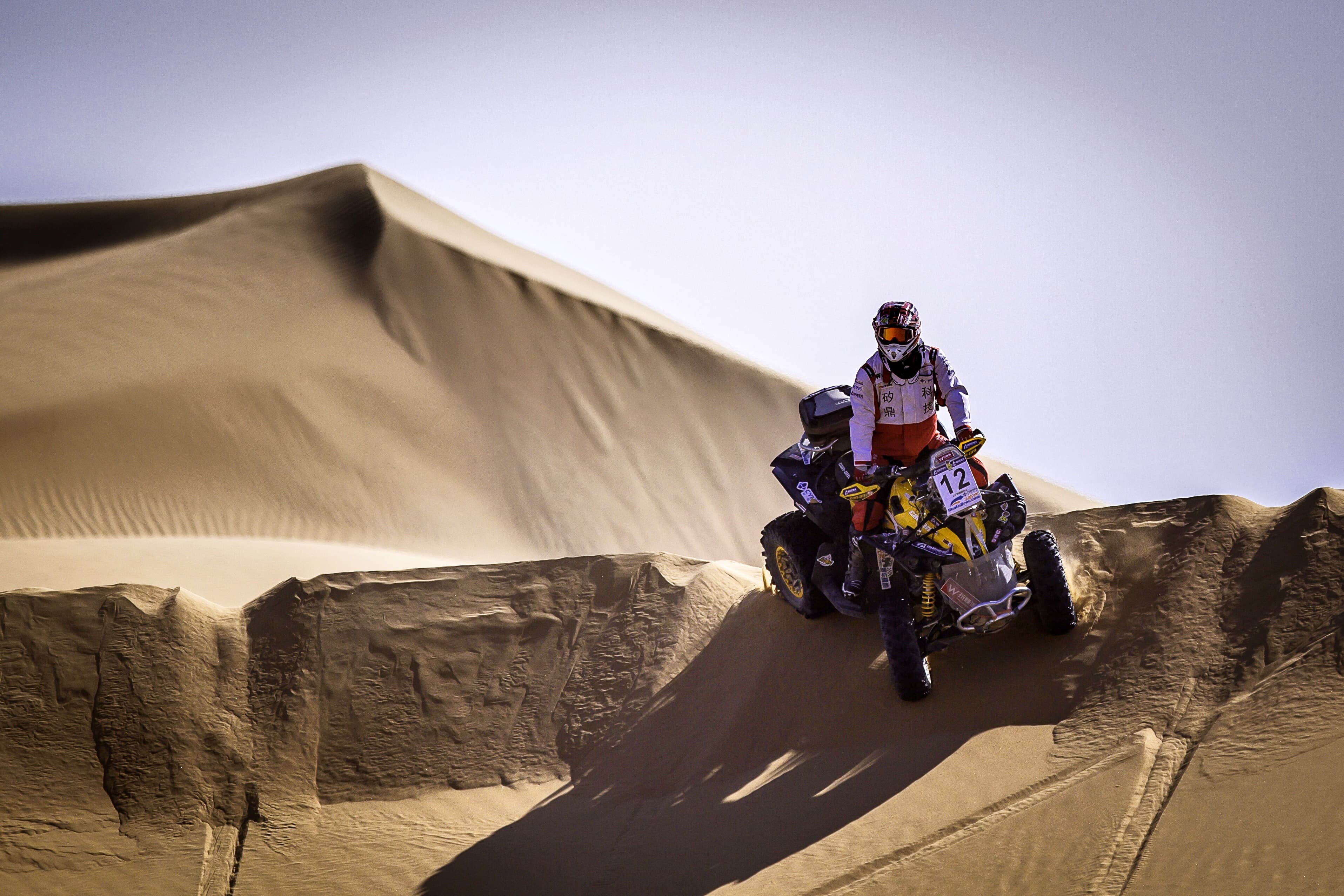 Li Tiejun riding an ATV over desert dunes